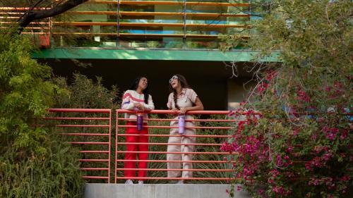 Two people stand on a vine-covered balcony while holding beautiful Stanley water bottles