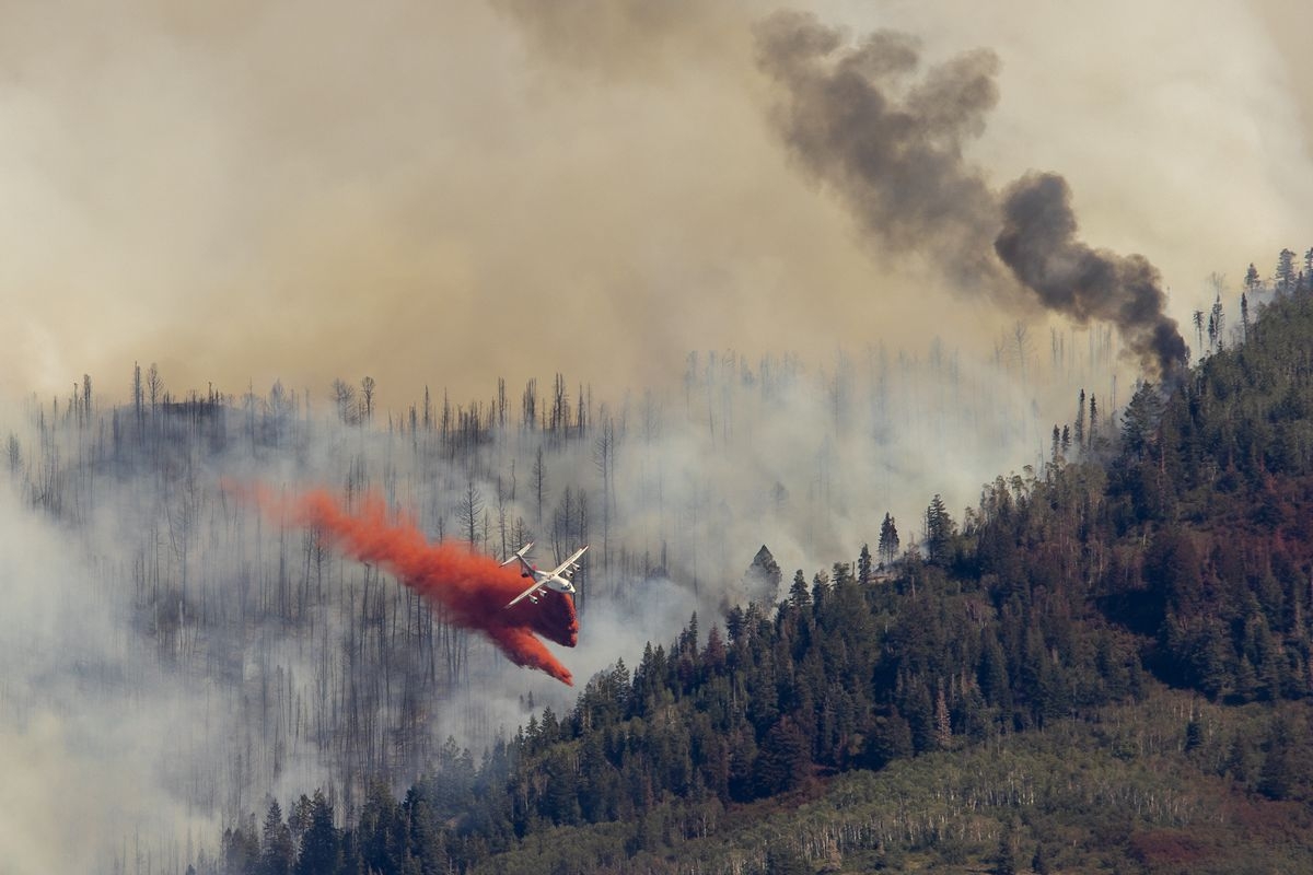 Plane fighting forest fire with red chemical