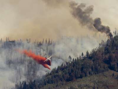 Plane fighting forest fire with red chemical
